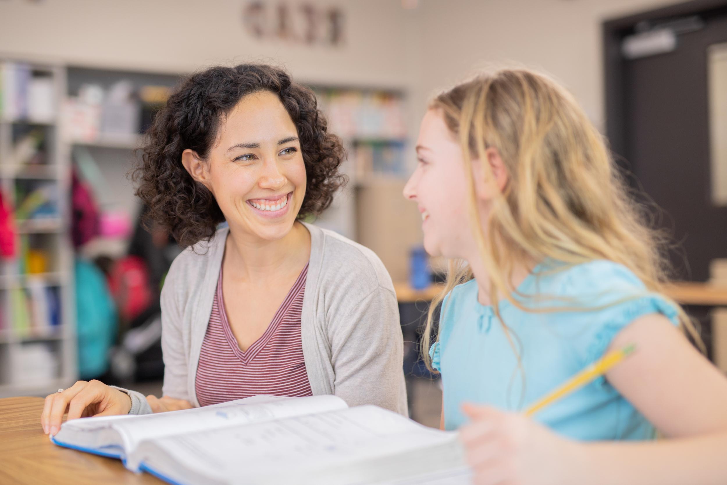 teacher helping elementary student in her classroom